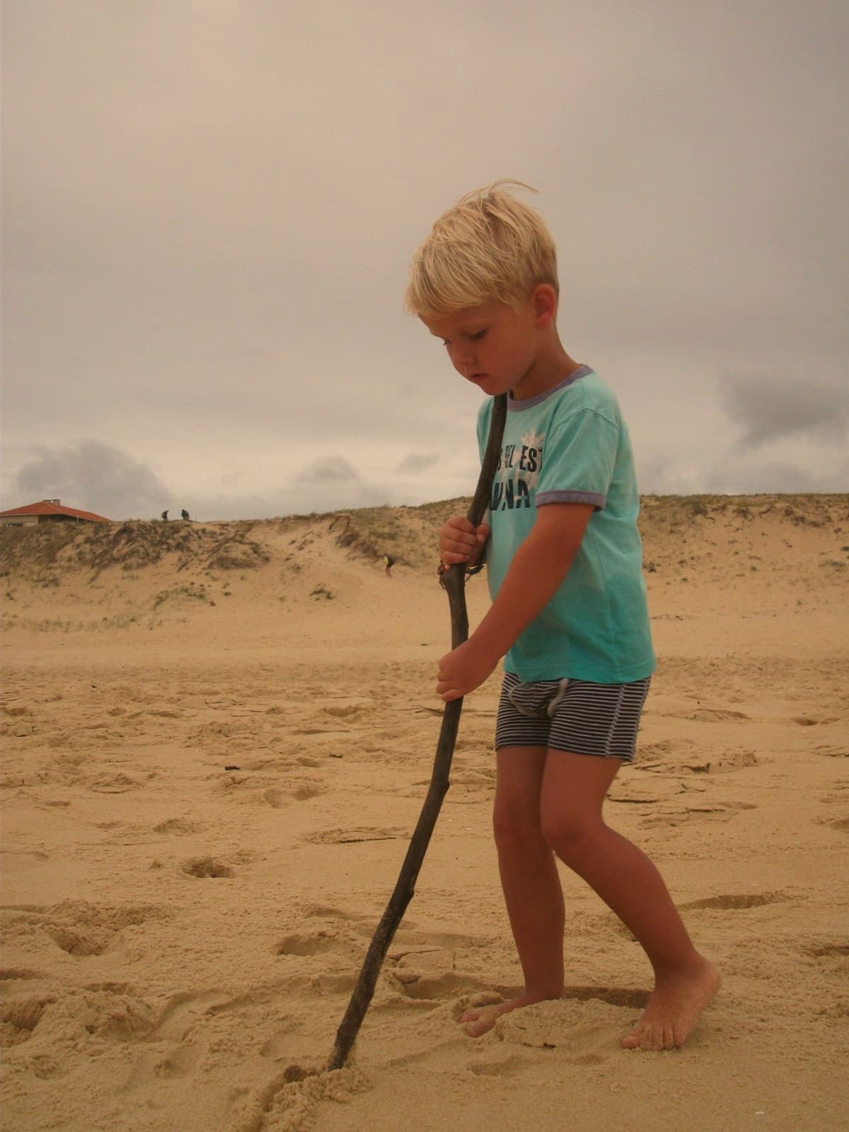 Jongen tekent met een stok een spoor in het zand
