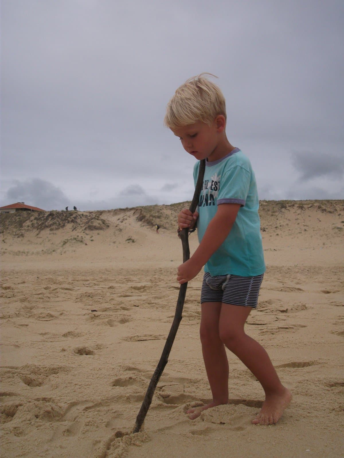 Jongen tekent met een stok een spoor in het zand