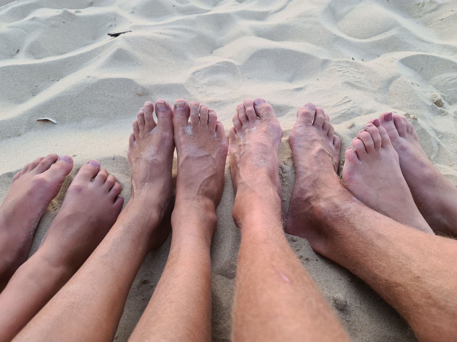 Voeten van ouder en kind in het zand - samen met ouders