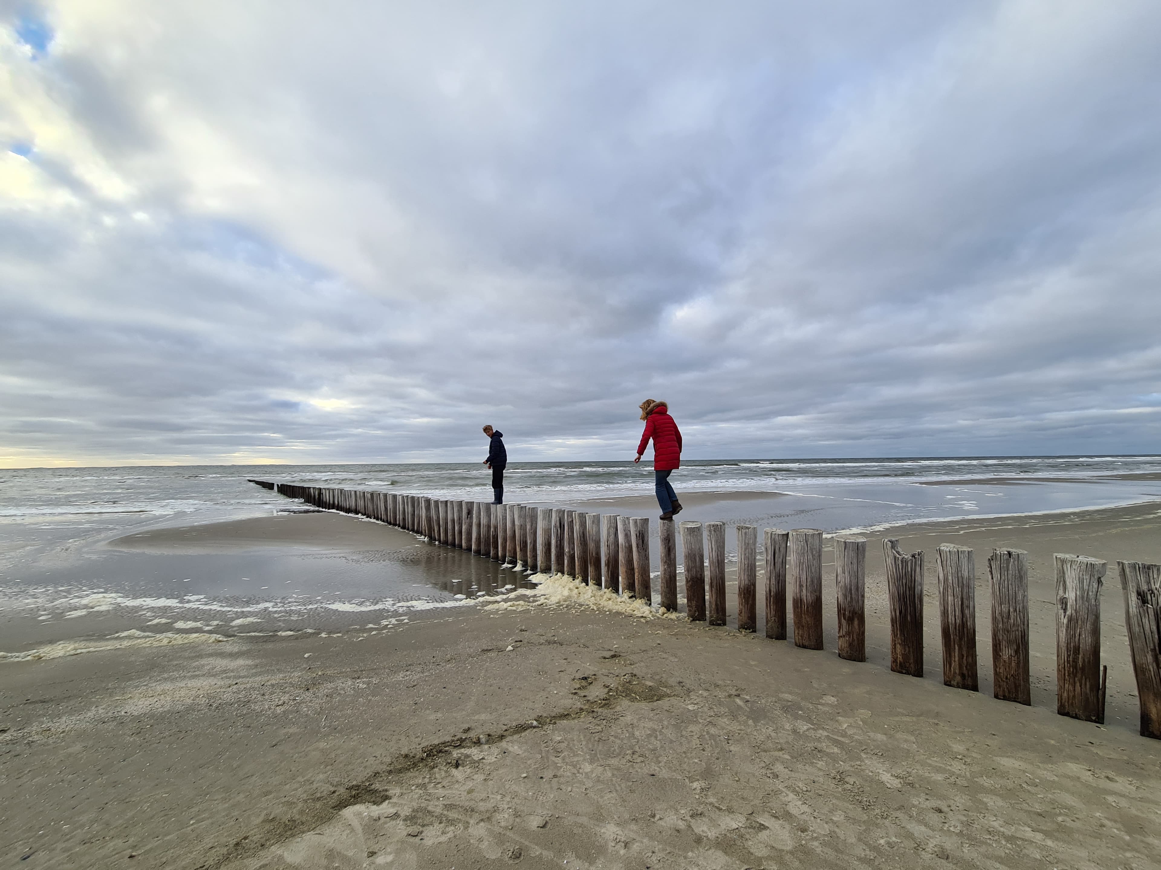 Twee figuren balanceren op paalhoofden in zee — beeld van de overgang in de Kind van 9-fase