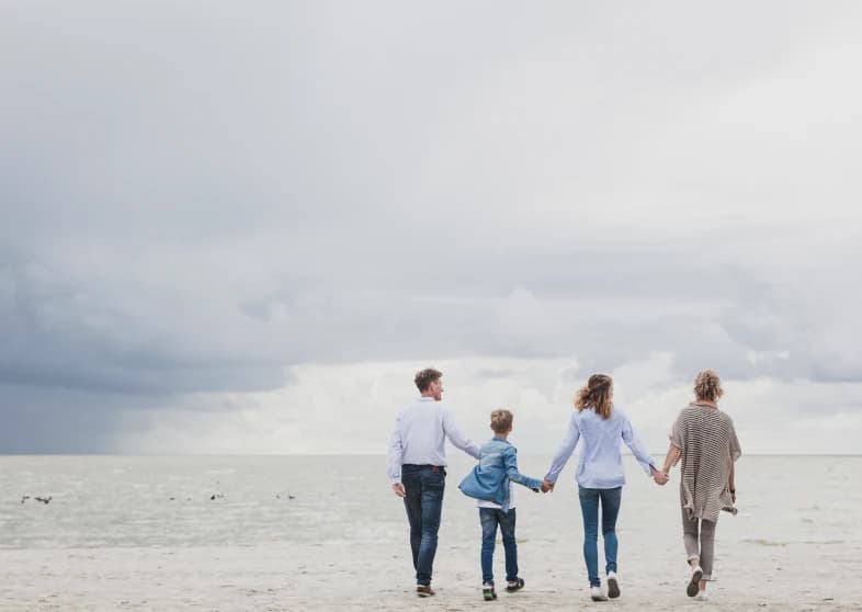 Hand in hand aan zee: Simone samen met een gezin aan de waterlijn