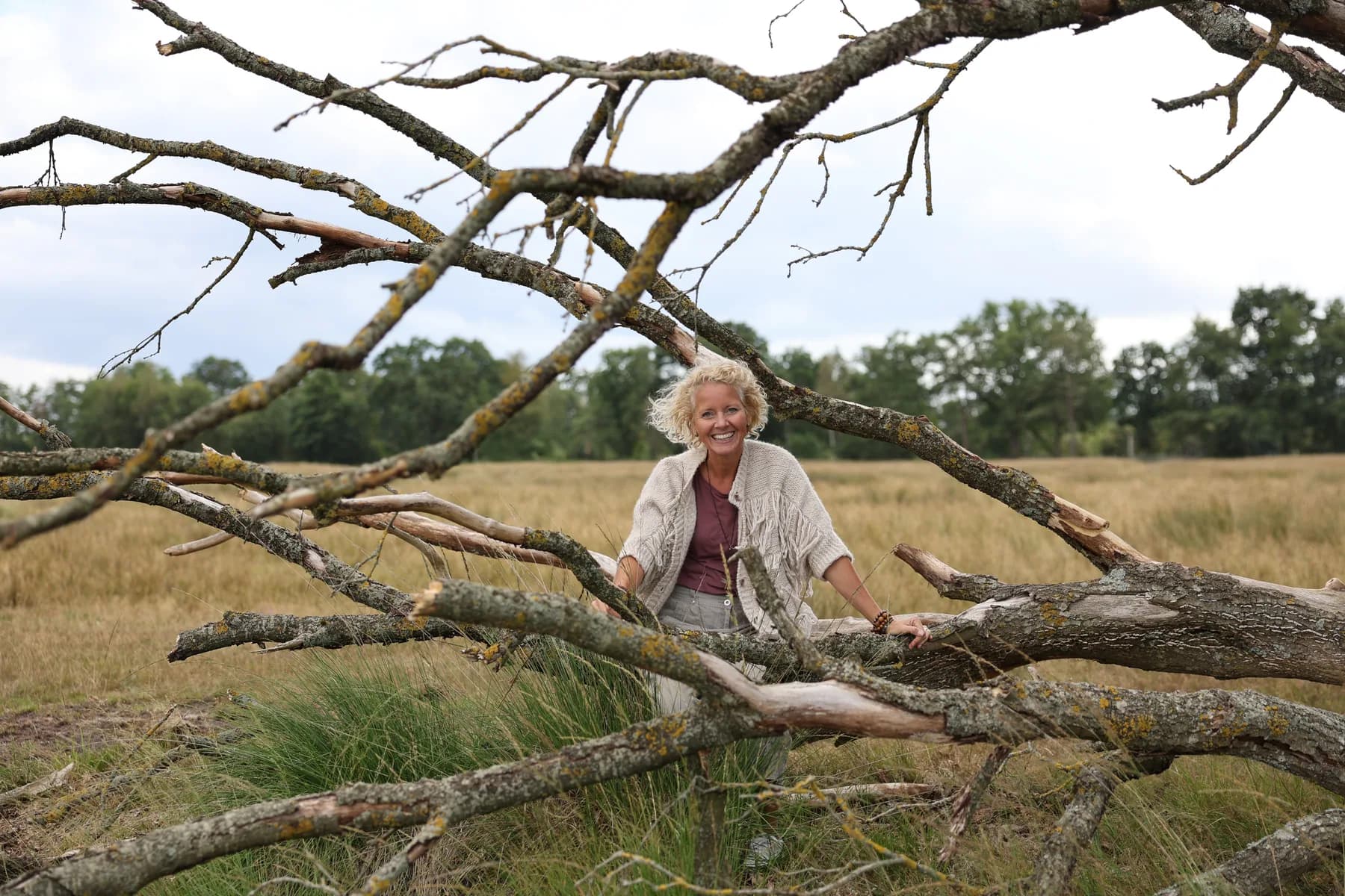 Simone Nieuwhuis tussen de grote boomtakken in een open landschap