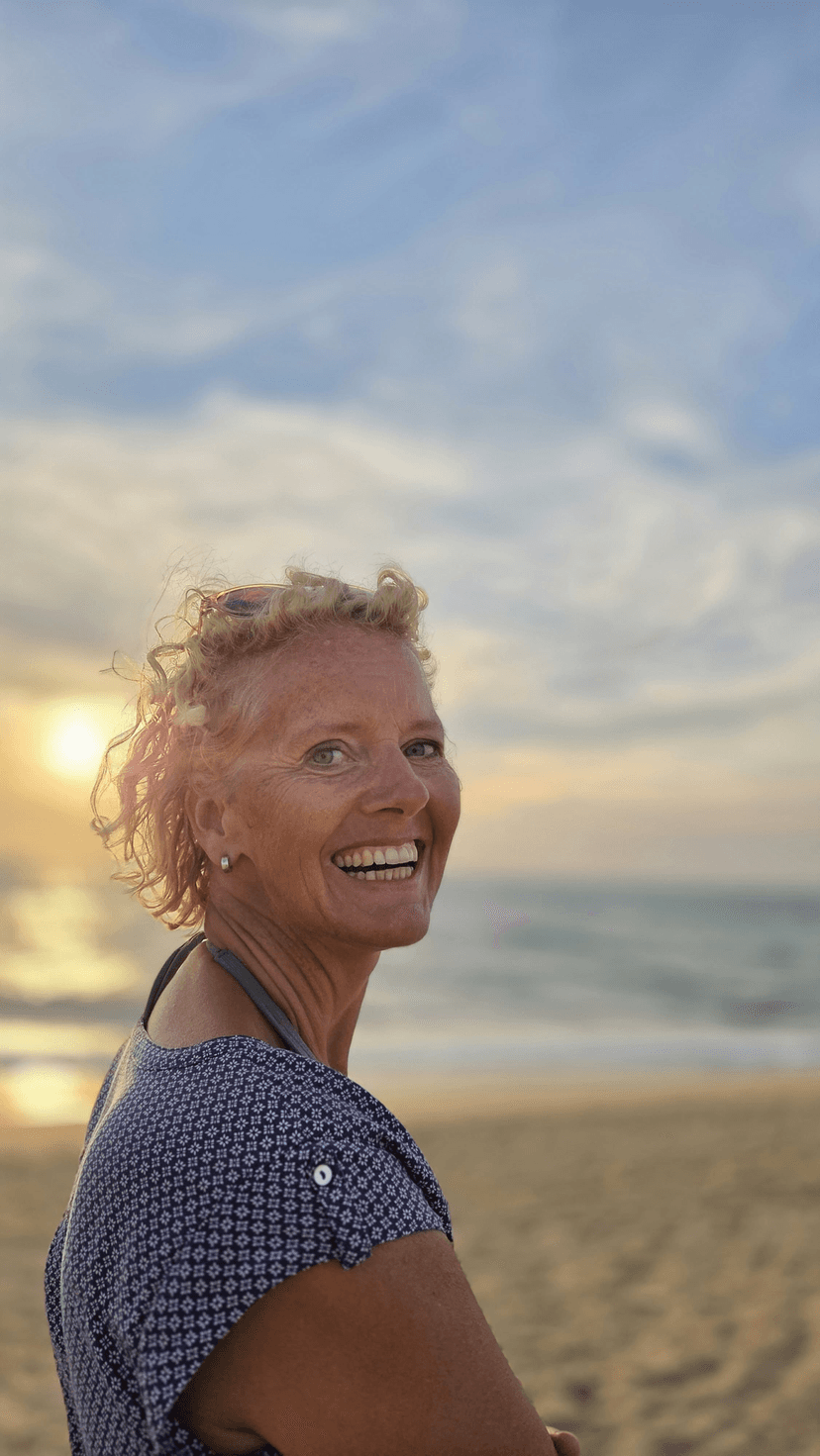 Simone Nieuwhuis - coach voor kleine en grote mensen, lachend op het strand bij zonsondergang